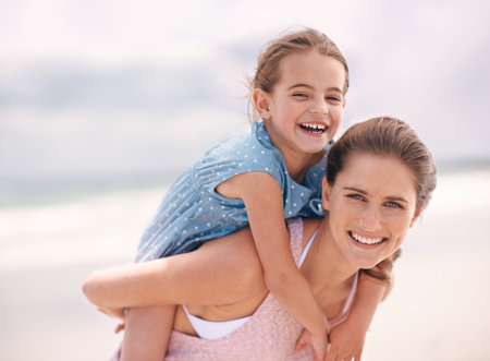 Spending quality time with mom. A little girl and her mother at the beach.の写真素材