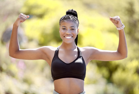 Sports woman with strong biceps doing exercise and training. Portrait of young black woman showing strength, fitness and muscles after exercising outside in nature. Motivation and workout for femaleの写真素材