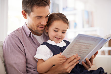 Her favourite story. a young father reading a book with his daughter.の写真素材