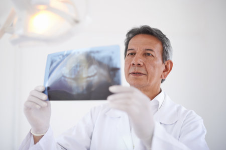 Hes checking on your teeth. a dentist looking at an x-ray.の写真素材