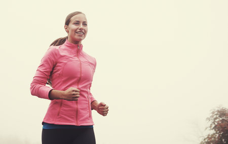 I love a misty morning run. A young woman jogging on a country road on a misty morning.の写真素材
