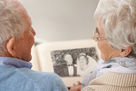 I remember the day so well...a senior couple leafing through their wedding album.の写真素材