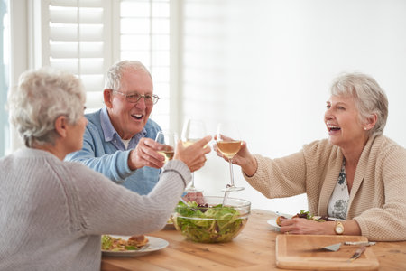 Food is better when we eat it together. A senior man and two senior women enjoying lunch.の写真素材