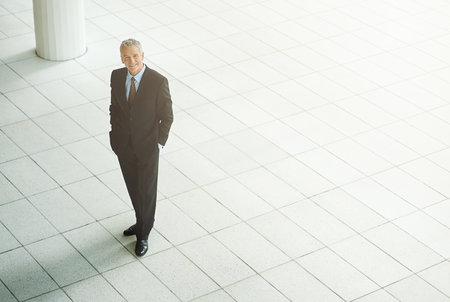 Hes a titan of business. High angle portrait of a mature businessman standing in an office lobby.の写真素材