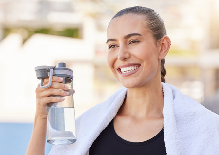 Fitness, athlete woman with water bottle for her exercise or outdoor workout with sunshine and a smile, Young sports person drink water during training for healthy lifestyle, wellness and body goalの写真素材