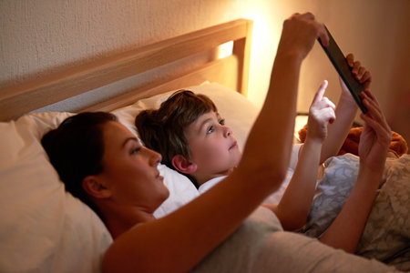 Interactive bedtime stories. a mother and son using a digital tablet together while lying in bed.