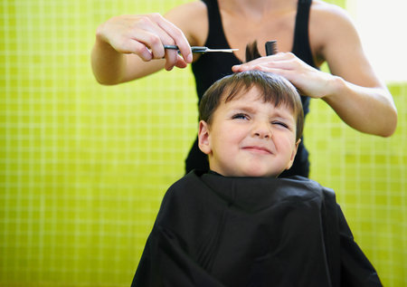 So far hes not liking the whole hair-dressing experience. a young boy getting his first haircut.の写真素材