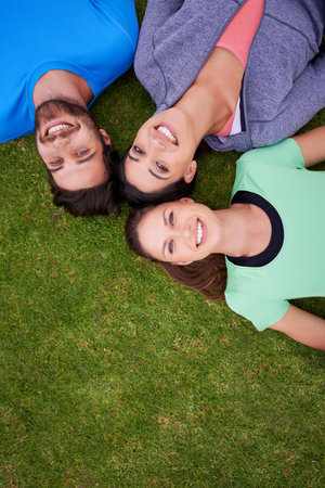 They are inseparable. High angle shot of a three friends lying down on grass.の写真素材