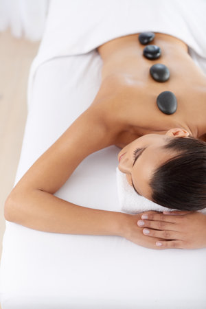 Hot stone massage. a beautiful young woman relaxing during spa treatment.の写真素材