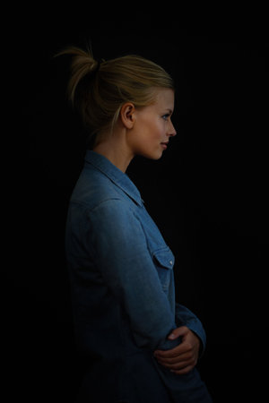 Brodd. A young woman in a denim shirt against a dark background.の写真素材