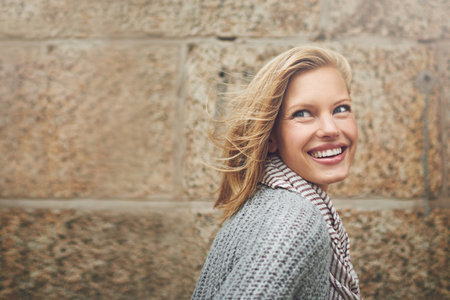 She belongs in the city. an attractive young woman standing outside against a brick wall.の写真素材