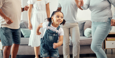 Happy girl with family dancing in living room while playing, having fun and enjoy bonding quality time together. Happy family love, connection and freedom for youth child or kid at home dance partyの写真素材