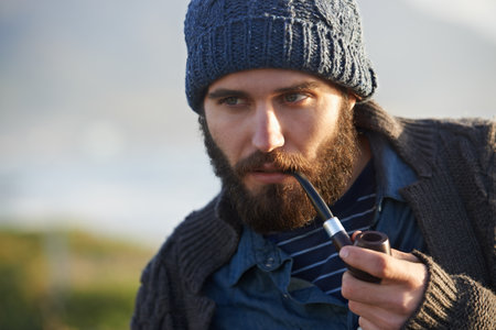 Smoking a pipe. a bearded man smoking a pipe outside.の写真素材