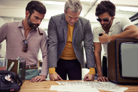 Well, here are our choices...Three designers clad in retro 70s wear working on a project together.の写真素材