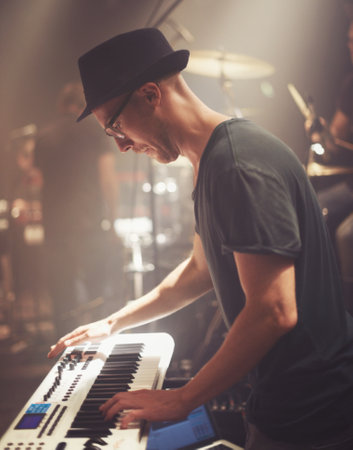 He has the world of music at his fingertips. A young man playing a keyboard on stage at a music concert.の写真素材