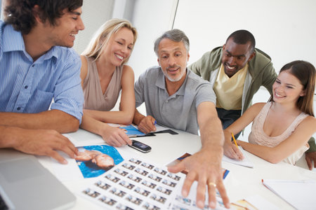 Choosing the best picture for the project. A group of designers discussing image choices.の写真素材