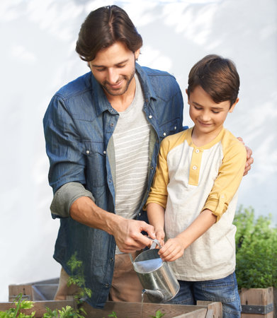 The guys with the green thumbs. a father and son watering the plants in their herb garden.の写真素材