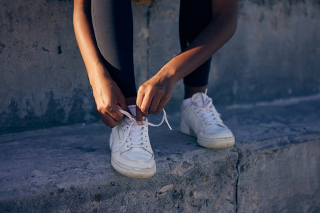 Safety first. Keep your laces tied. High angle shot of an unrecognizable woman tying her laces while standing on a step outside.の写真素材