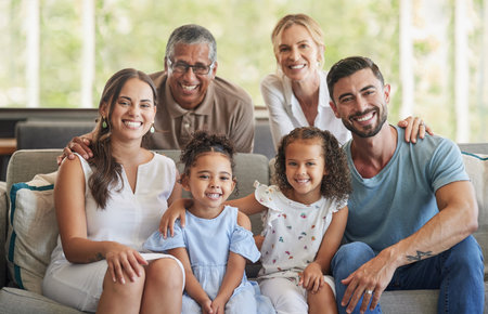 Happy big family, portrait and smile on sofa in home living room, spending quality time and bonding. Love, support and care of grandparents, parents and girls together on house couch smiling or laughの写真素材