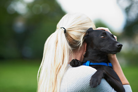 I love my dog. A woman holding her black canine in the outdoors.の写真素材
