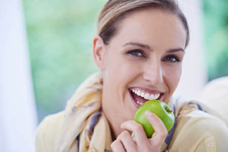 Choose a healthy snack. Portrait of a beautiful woman holding a apple.の写真素材