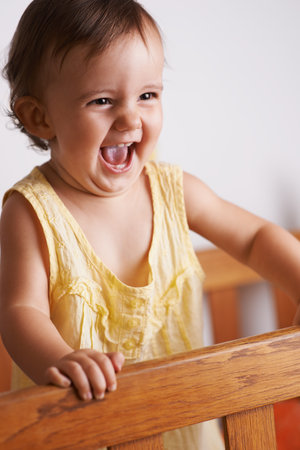 Enjoying her new-found standing skill. A cute litlle girl laughing as she stands up in her crib.の写真素材