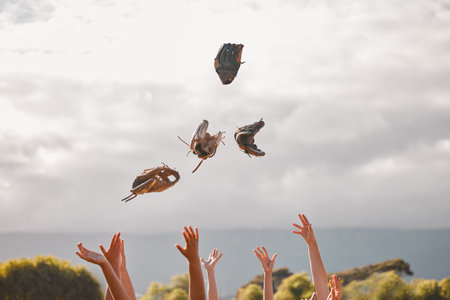Team celebrate winning, game of baseball or trophy by throw gloves in air. Softball squad happy for victory in championship or competition together, lift hands to the sky in happiness and celebrationの写真素材
