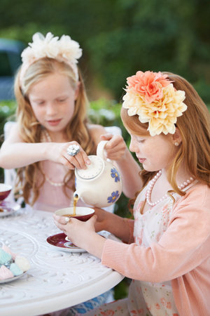 Fancy a spot of tea love. Two young girls having a tea party in the backyard.の写真素材
