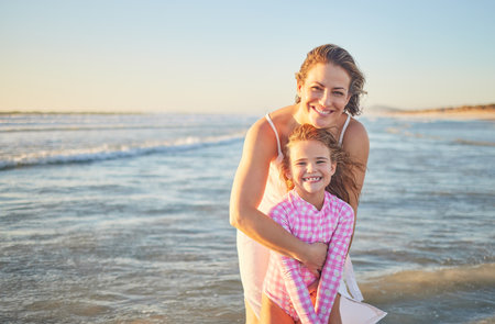 Mother, child and ocean smile in water, happy and fun time together on family vacation by the sea. Woman, girl and beach playing in waves and show happiness while on holiday or travel to Miamiの写真素材