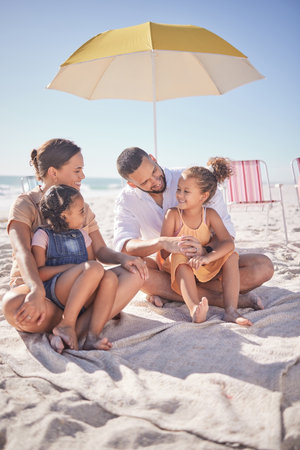 Family, happy and ocean summer experience of a mother, man and children enjoying the sea on sand. Happiness smile of kids and people together with quality time sitting in nature with a beach umbrellaの写真素材