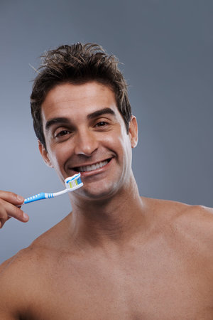 Hes committed to dental hygiene. Studio portrait of a bare-chested young man about to brush his teeth.の写真素材