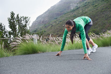 Ready to make this road her own...A young woman crouching on the street about to go for a run.