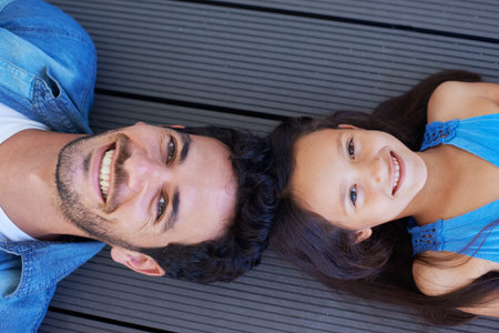 Fun with dad. High angle portrait of a father and daughter lying on the floor and smiling up at the camera.の写真素材