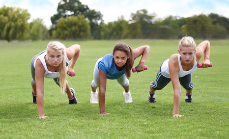 Working out as a team. a group of young women working out with dumbbells.