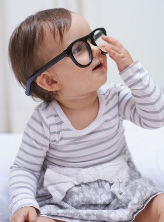 Shes destined for great things. A cute little baby girl wearing over-sized spectacles.の写真素材