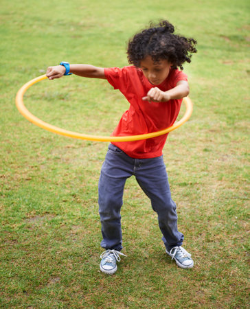 Hula-hoop. A young ethnic boy playing with a hula-hoop outside.の写真素材