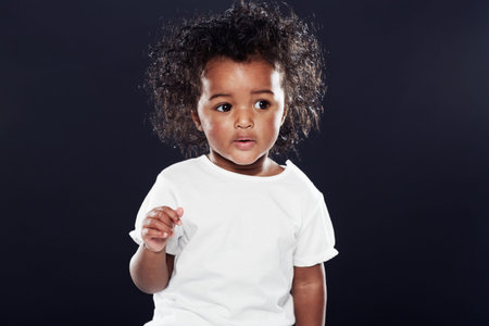 The curious one. a cute girl on a black background.の写真素材