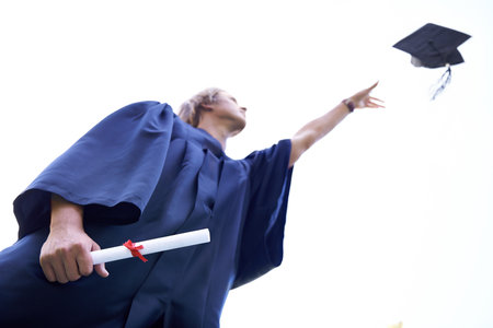 I did it. A graduate throwing his graduate hat in the air while holding his diploma.の写真素材