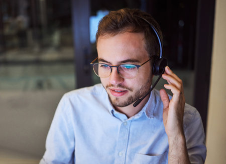 Call center, customer service and telemarketing with a man working in support with a headset in his office. Sales, consulting and contact us with a male consultant at work in crm communicationの写真素材
