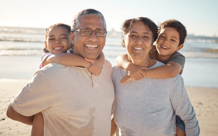 Family on beach with grandparents and kids for summer or holiday, senior wellness and growth development. Young happy kids with grandmother and grandfather with sunshine, ocean for outdoor funの写真素材
