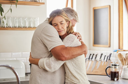 Couple, elderly and hug in kitchen in home together, romance and love. Care, man and woman in retirement love, marriage and embrace in sad moment for support, comfort and unity as married peopleの写真素材