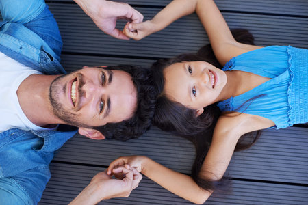 They take care of each other. High angle portrait of a father and daughter lying on the floor and holding hands.の写真素材