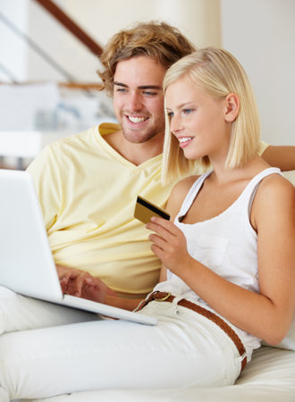 Making use of their credit card. A happy young couple buying online with their credit card.の写真素材
