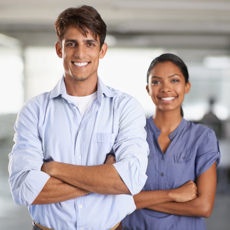 Positive work environment. A young business team standing with arms folded.