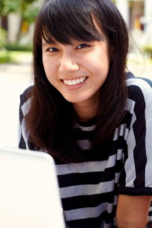 Campus life. Portrait of an attractive young female student using her laptop on campus.の写真素材