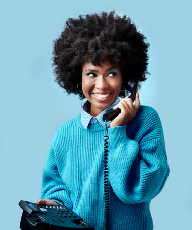 Landline, communication and black woman talking on a telephone against a blue mockup studio background. Happy, smile and young African model speaking to contact on a vintage phone with mock up spaceの写真素材