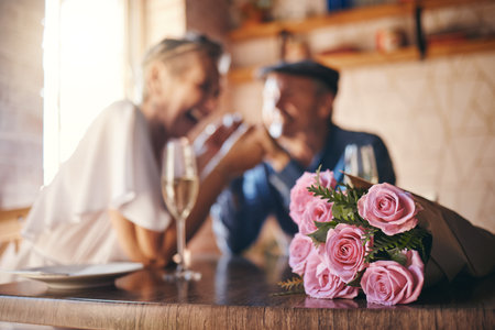 Love, celebration and of roses for couple marriage anniversary with champagne for toast. Romantic, happy and caring senior people in relationship commitment together enjoy intimate date.の写真素材
