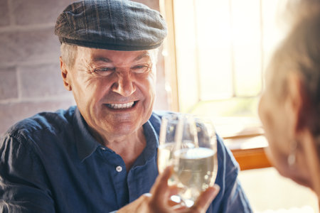 Champagne toast, celebration and senior couple with smile about retirement at restaurant. Elderly man and woman at dinner to celebrate anniversary, marriage and love with drink of wine and cheersの写真素材
