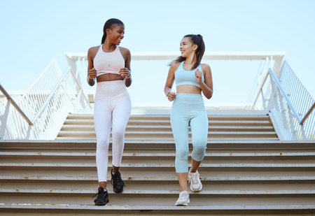 Fitness, health and exercise with personal trainer and woman workout on stairs, talking and bonding. Friends training and cardio workout by cheerful ladies enjoying healthy lifestyle and morning runの写真素材