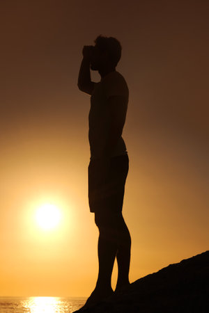 Appreciating the beauty of nature. Silhouette of a man looking over the ocean - profile.の写真素材
